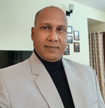 Man in a checked blazer and black turtleneck indoors.