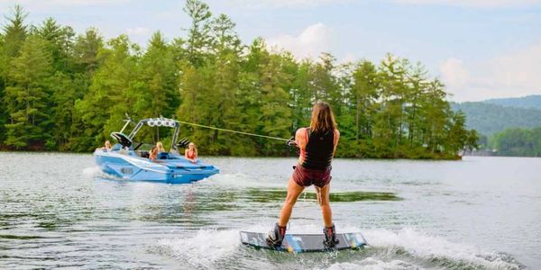 Person wakeboarding on a lake being towed by a boat with passengers.