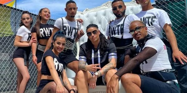 Group of dancers posing outdoors with stylish outfits and sunglasses.