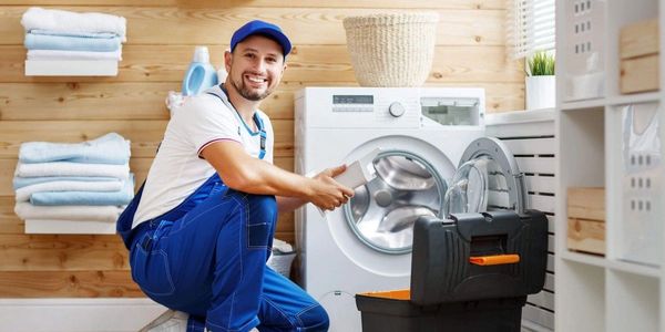 Plumber with toolbox in front of washing machine after been connected 