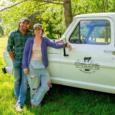 Happy couple standing by a vintage farm truck on a sunny day.