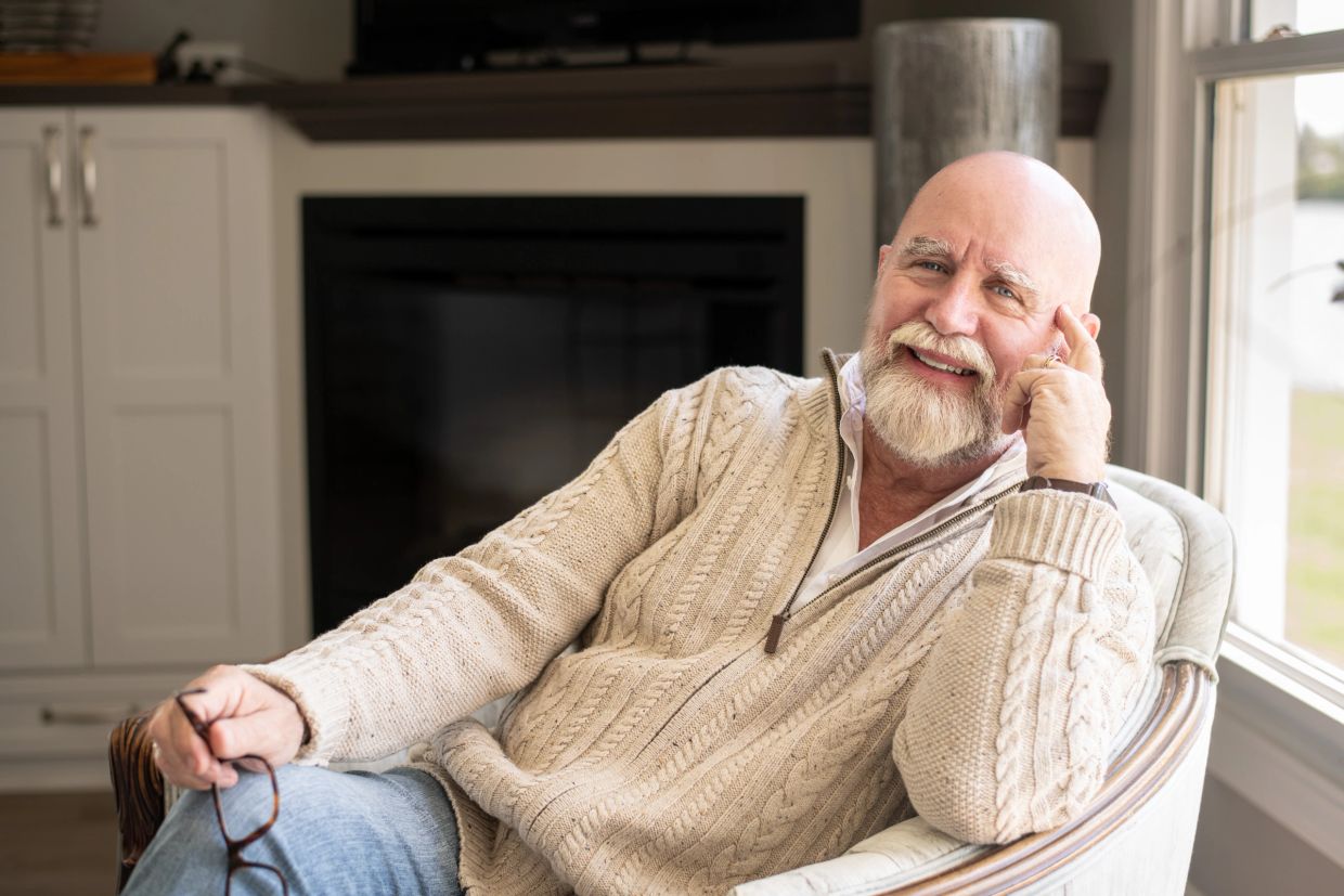 Smiling elderly man sitting comfortably in a chair.