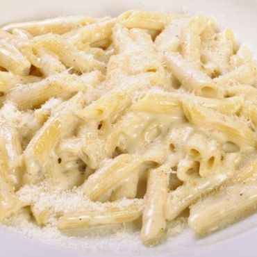 Plato de pasta penne con una salsa de cuatro quesos cremosa.