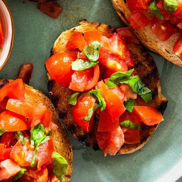 Pan campesino tostado, tomates picados sazonados con aceite extra de oliva, ajo, sal y albahaca.