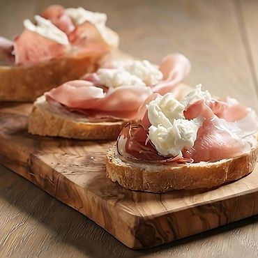 Pan campesino tostado, con una deliciosa capa de crema de burrata y speck en lonjas.