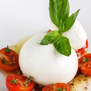 Cremosa Burrata sobre pesto genovés, enmarcada con jugosos tomates cherry, acompañada de pan campesi