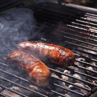 Salchichas chisporroteantes a la parrilla en una barbacoa,