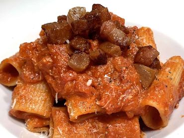 Plato de rigatoni a la Amatriciana con salsa de tomate y guanciale.