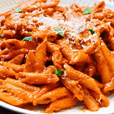 Plato de pasta penne con pesto a la calabrese, hecho con pimientos, tomate y queso ricotta.