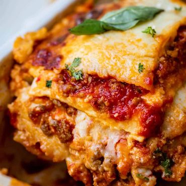 Lasaña a la boloñesa con capas de pasta, ragú, salsa bechamel y queso gratinado.