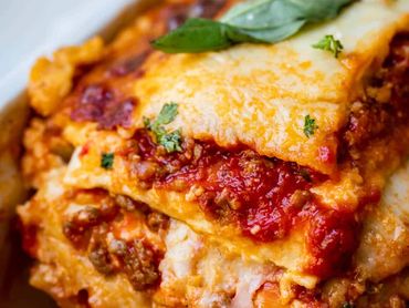 Lasaña a la boloñesa con capas de pasta, ragú, salsa bechamel y queso gratinado.