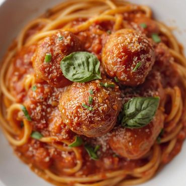 Plato de espaguetis con albóndigas en salsa de tomate y queso parmesano.