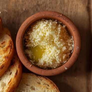 Parmesano servido con un toque de aceite de oliva virgen en una cazuela y pan campesino tostado.