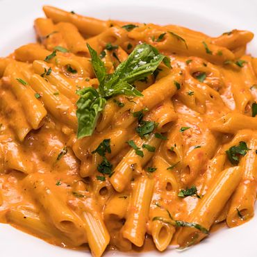 Plato de penne en salsa cremosa de vodka con tocineta crujiente.