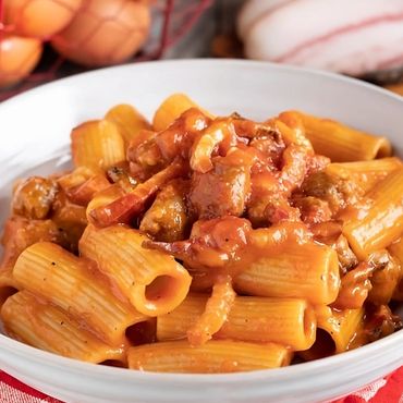 Plato de rigatoni a la Zozzona con salsa de tomate, guanciale y salchicha.