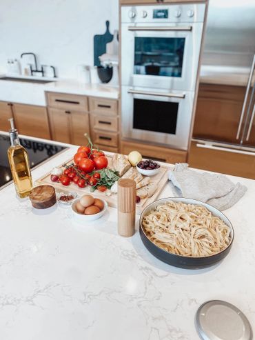 Fresh ingredients and pasta prepared on a kitchen counter.