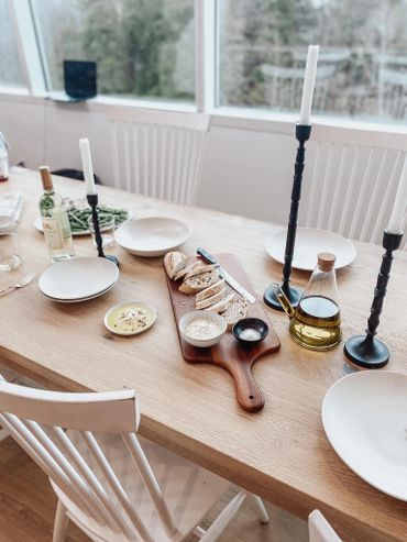 A cozy dining table set with bread, olive oil, and candles.