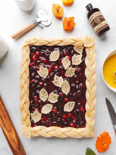 Rectangular berry pie with braided crust and leaf decorations.