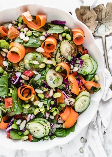 edamame salad in white scalloped bowl with carrot ribbons and cucumbers made by Chicago Food Stylist