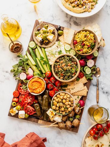A colorful Mediterranean platter with vegetables, dips, and flatbread.