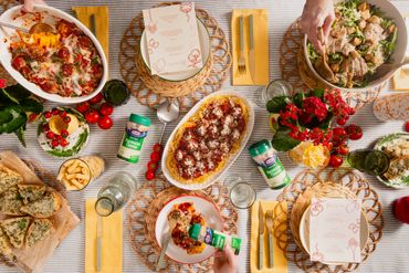 A beautifully arranged Italian meal with pasta, salad, and parmesan on a dining table.
