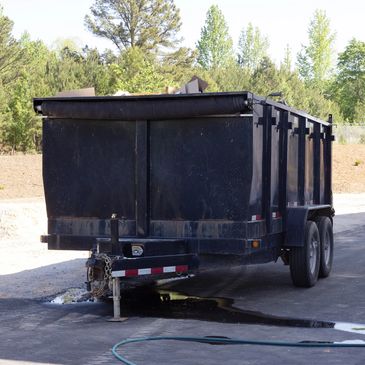 Black utility trailer parked outdoors on a sunny day.