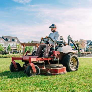 Man mowing a large lawn with a zero-turn mower.