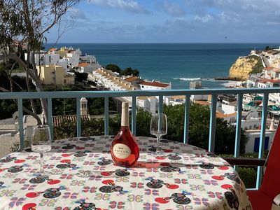 Table with wine and glasses overlooking a coastal town and ocean view.