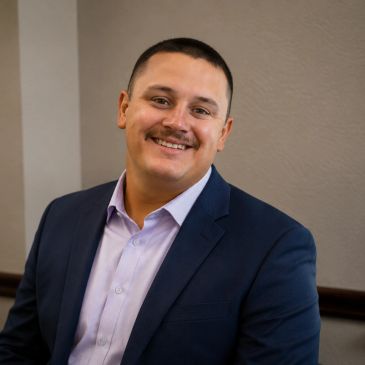 Man in navy blue suit smiling.