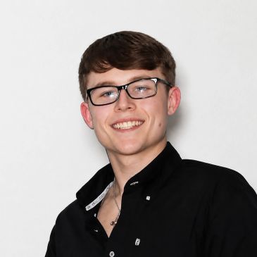 Young man smiling with glasses and black shirt.