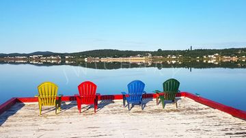 Four brightly colored chairs at the end of a dock 