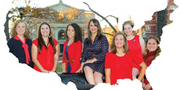 Seven women posing outdoors in fall, shaped like the United States.