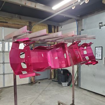 Metal frame painted bright pink in a workshop.