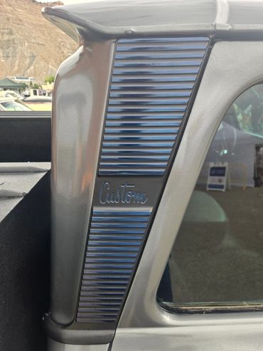 Close-up of a car window frame with "Custom" badge.