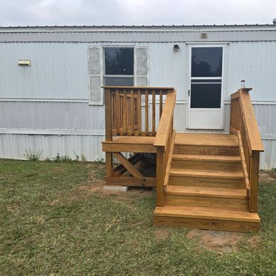 Wooden stairs leading to a white mobile home door.