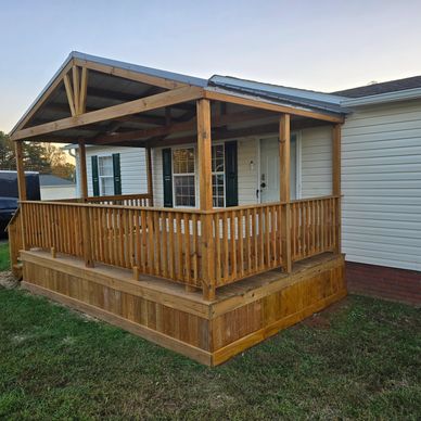 Wooden porch with railing and roof attached to a house.