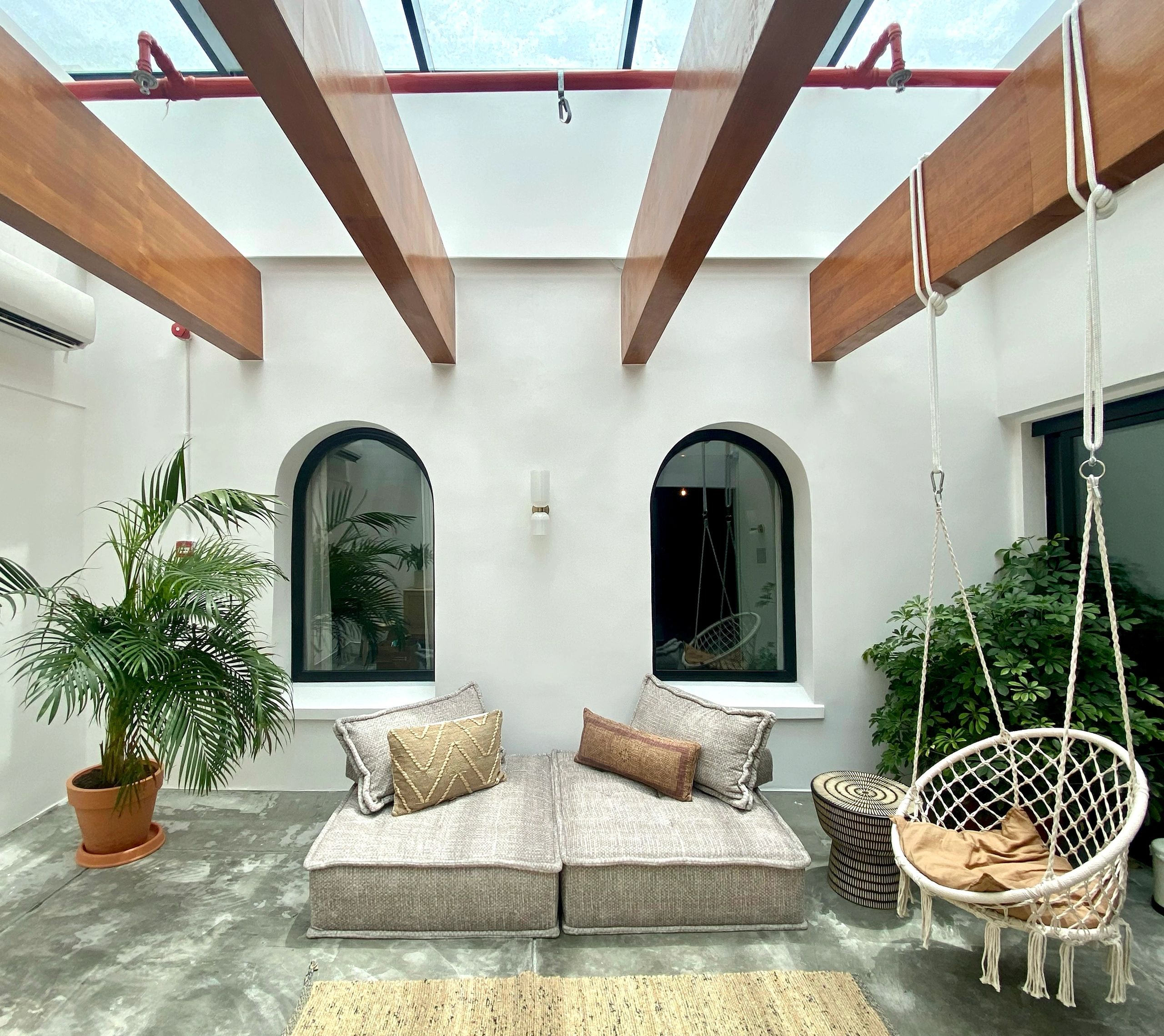 Cozy indoor seating area with hanging chair and skylight.