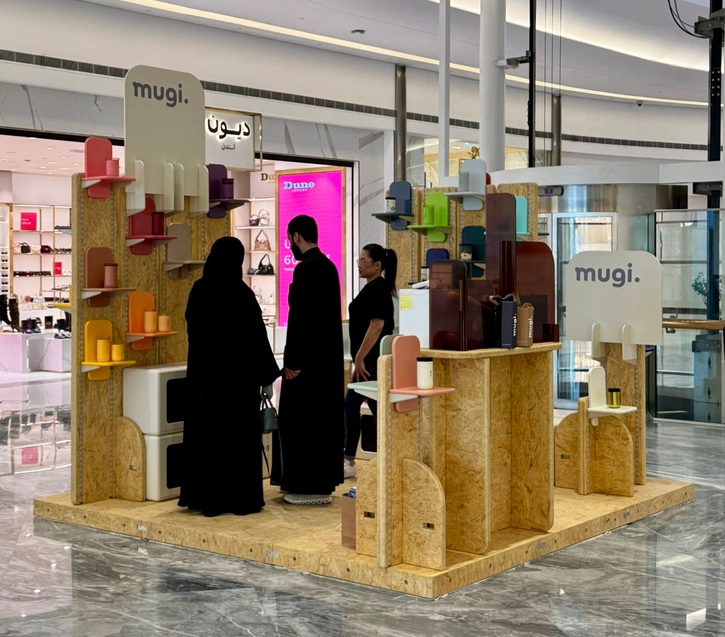 A modern kiosk showcasing colorful products with customers browsing inside a shopping mall.