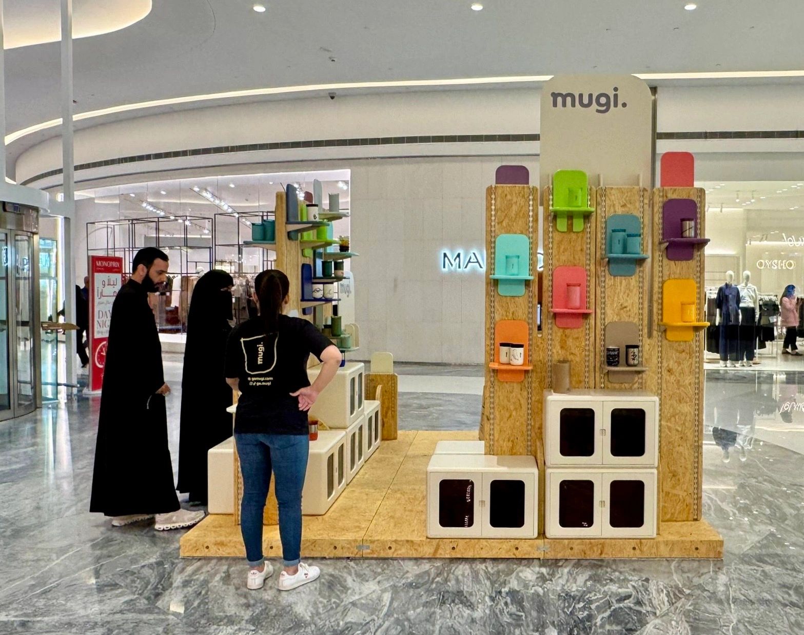 People observing a colorful display of portable speakers at a mall.