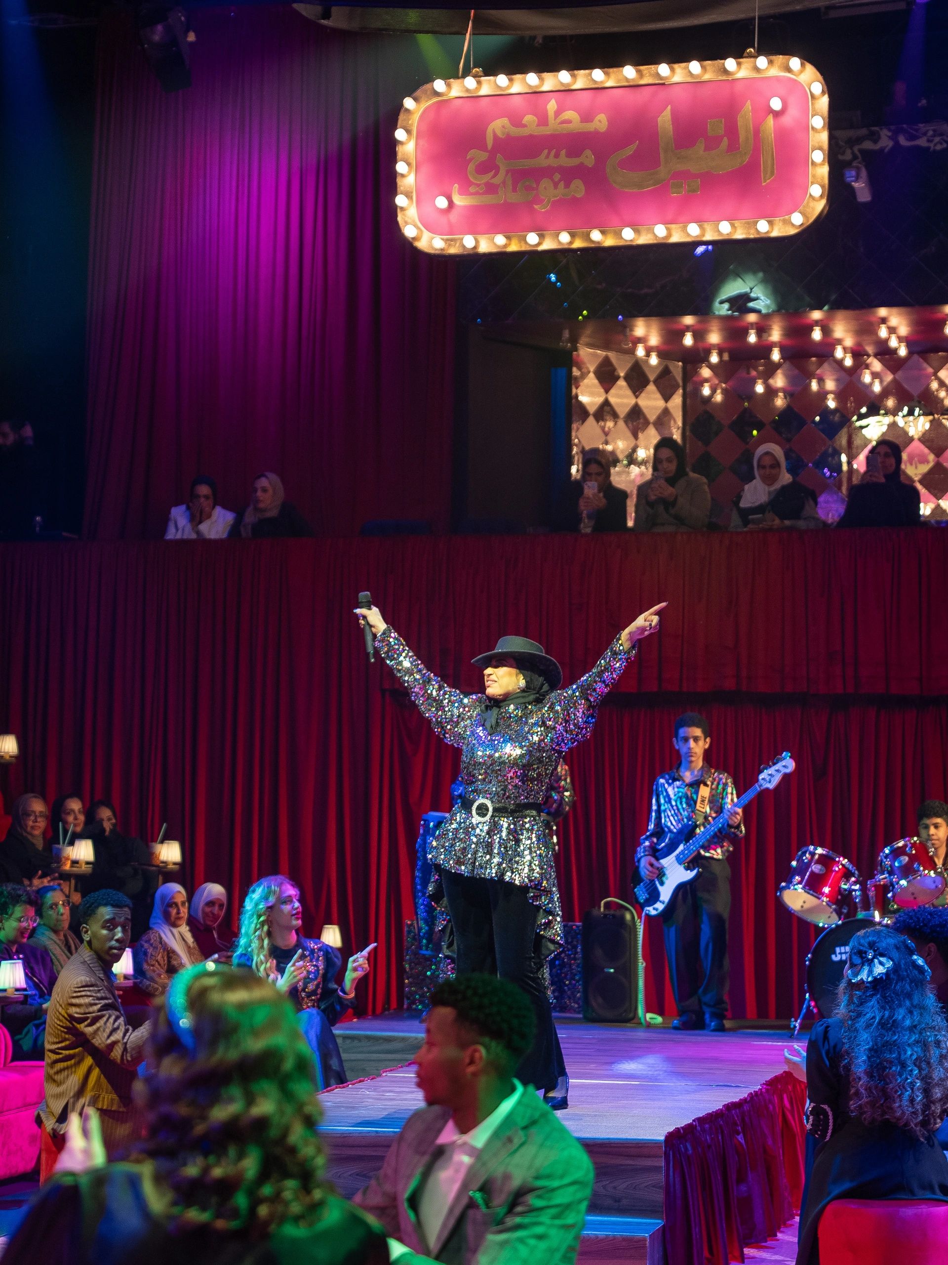 Performer singing on stage in a lively club.