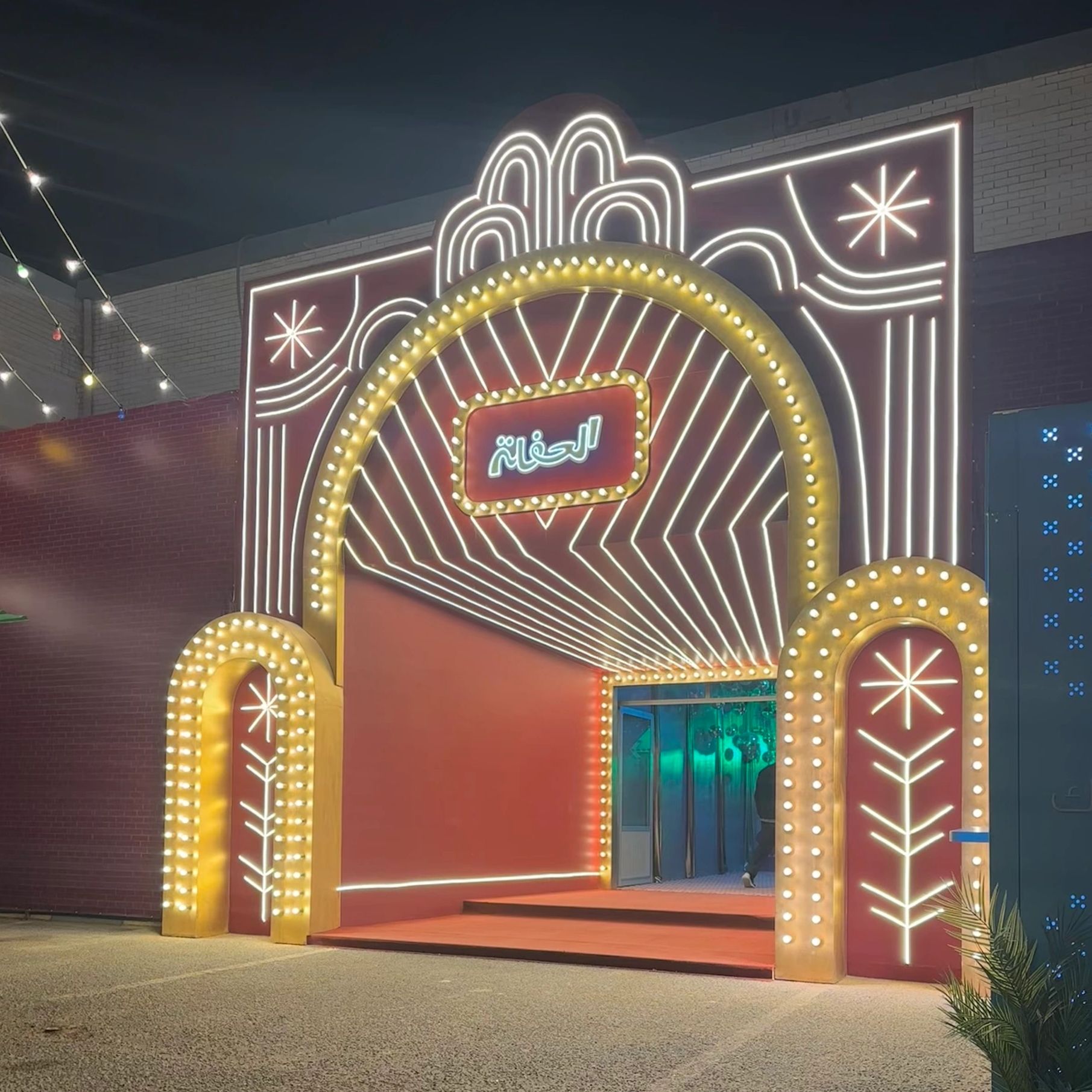 Illuminated archway entrance at night with Arabic sign.