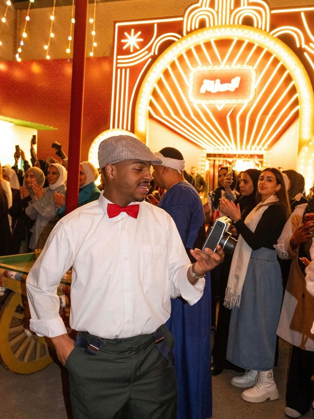 Man in white shirt and red bow tie looking at his phone.