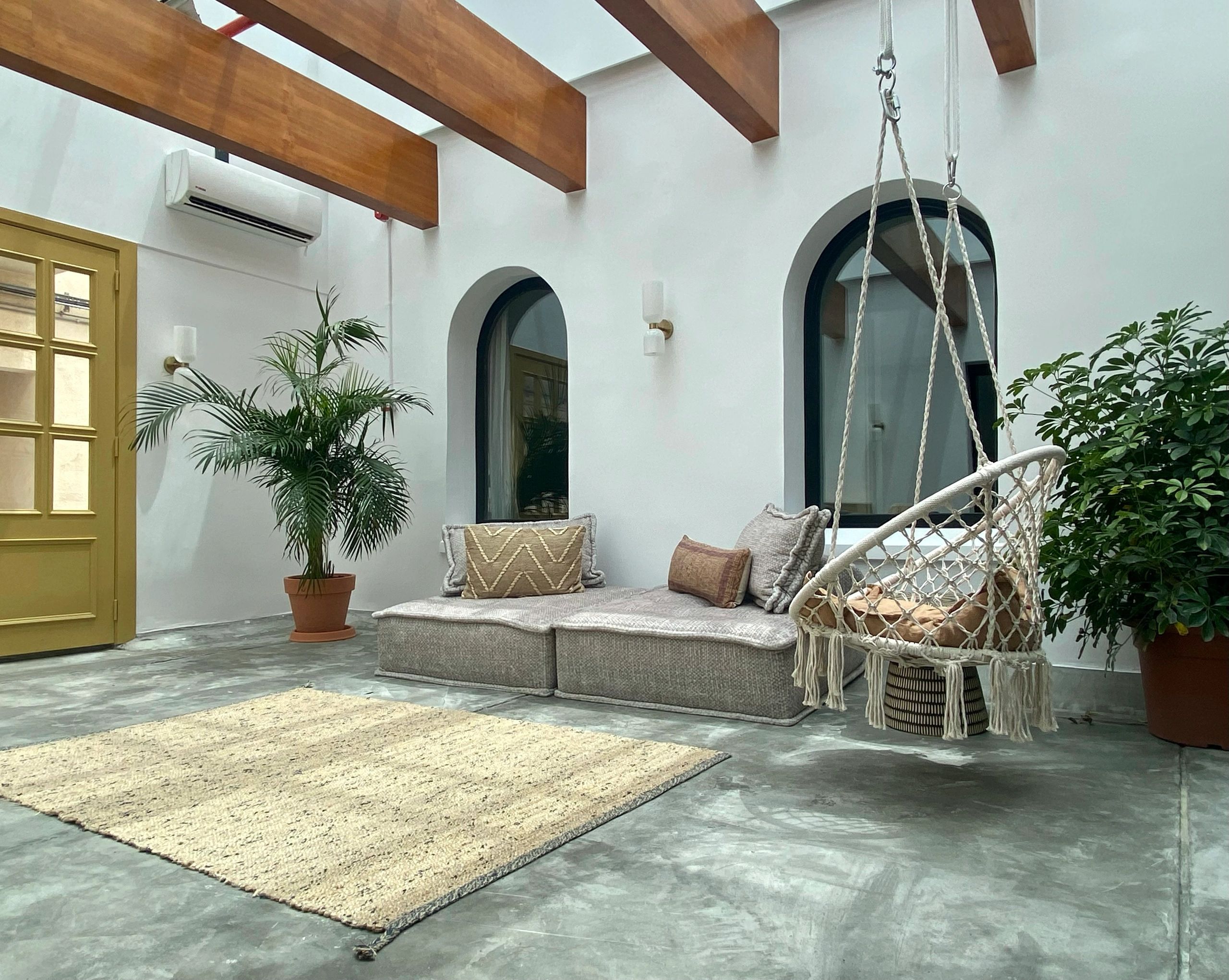 Bright indoor patio with hanging chair and cushioned seating.