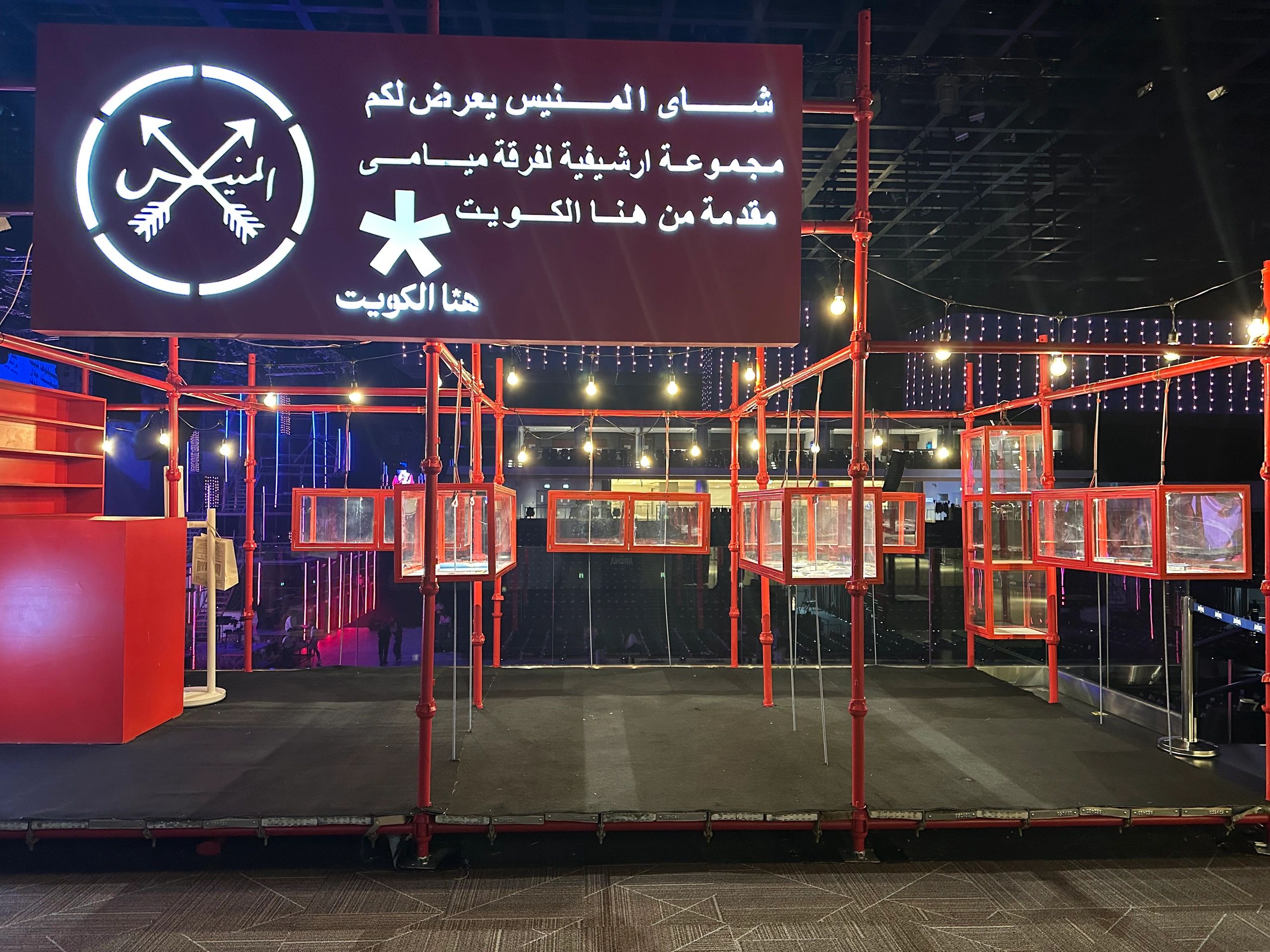 Modern interior with red-framed glass display cases and illuminated signs.