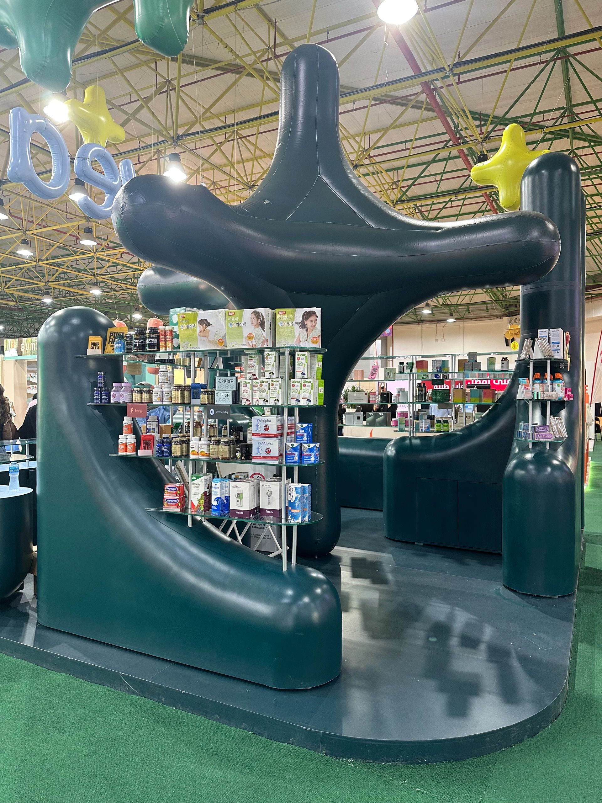 Modern retail display with curved dark green seats and assorted products on glass shelves.