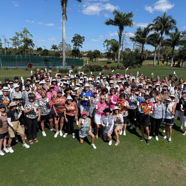 Large group of women gathered on a golf course on a sunny day.