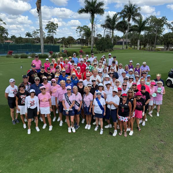 Large group photo on a golf course with colorful outfits.