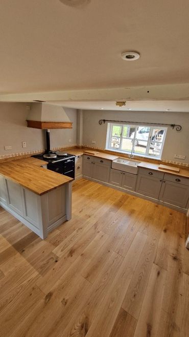 Modern kitchen with wooden floors and light cabinetry.