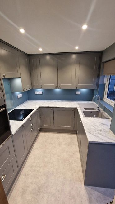 Modern kitchen with grey cabinets and marble countertops.