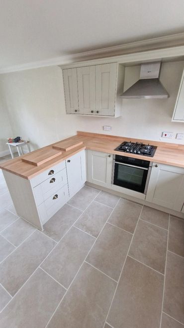 Modern kitchen with wooden countertops and tiled floor.